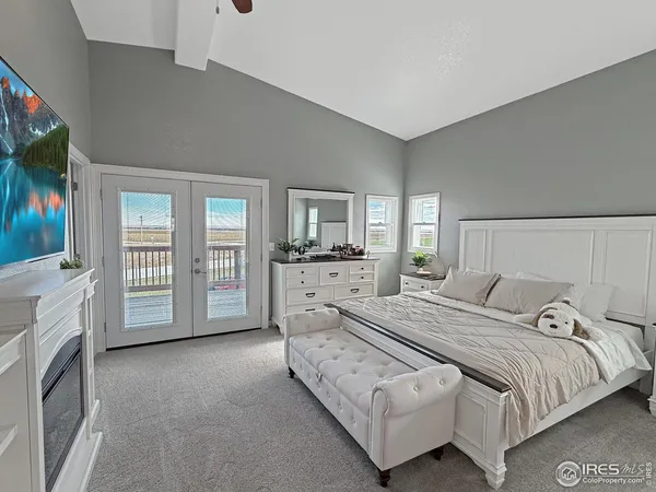 a spacious bedroom with a bed a flat screen tv and balcony view