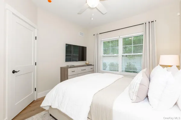 a bedroom with a bed and a flat tv screen on dresser