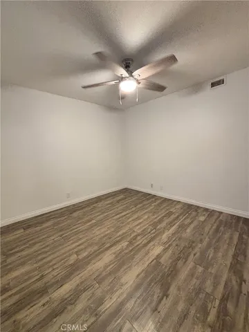 an empty room with wooden floor and fan