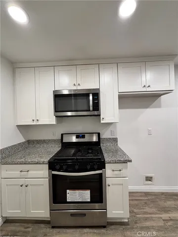 a kitchen with granite countertop white cabinets stainless steel appliances and a sink