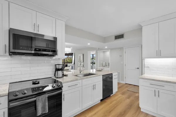 a kitchen with a refrigerator stainless steel appliances wooden floor and cabinets