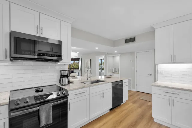 a kitchen with a refrigerator stainless steel appliances wooden floor and cabinets