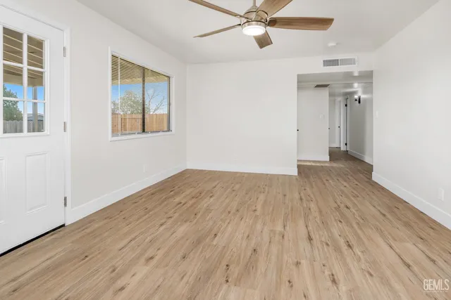 an empty room with wooden floor closet and windows