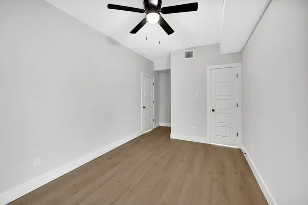 a view of empty room with wooden floor and ceiling fan