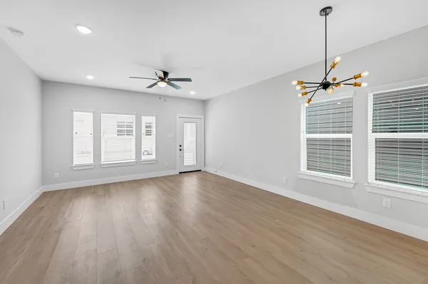 a view of an empty room with a window and wooden floor