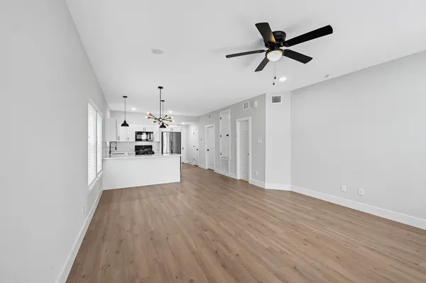 a view of a livingroom with a ceiling fan wooden floor and a ceiling fan