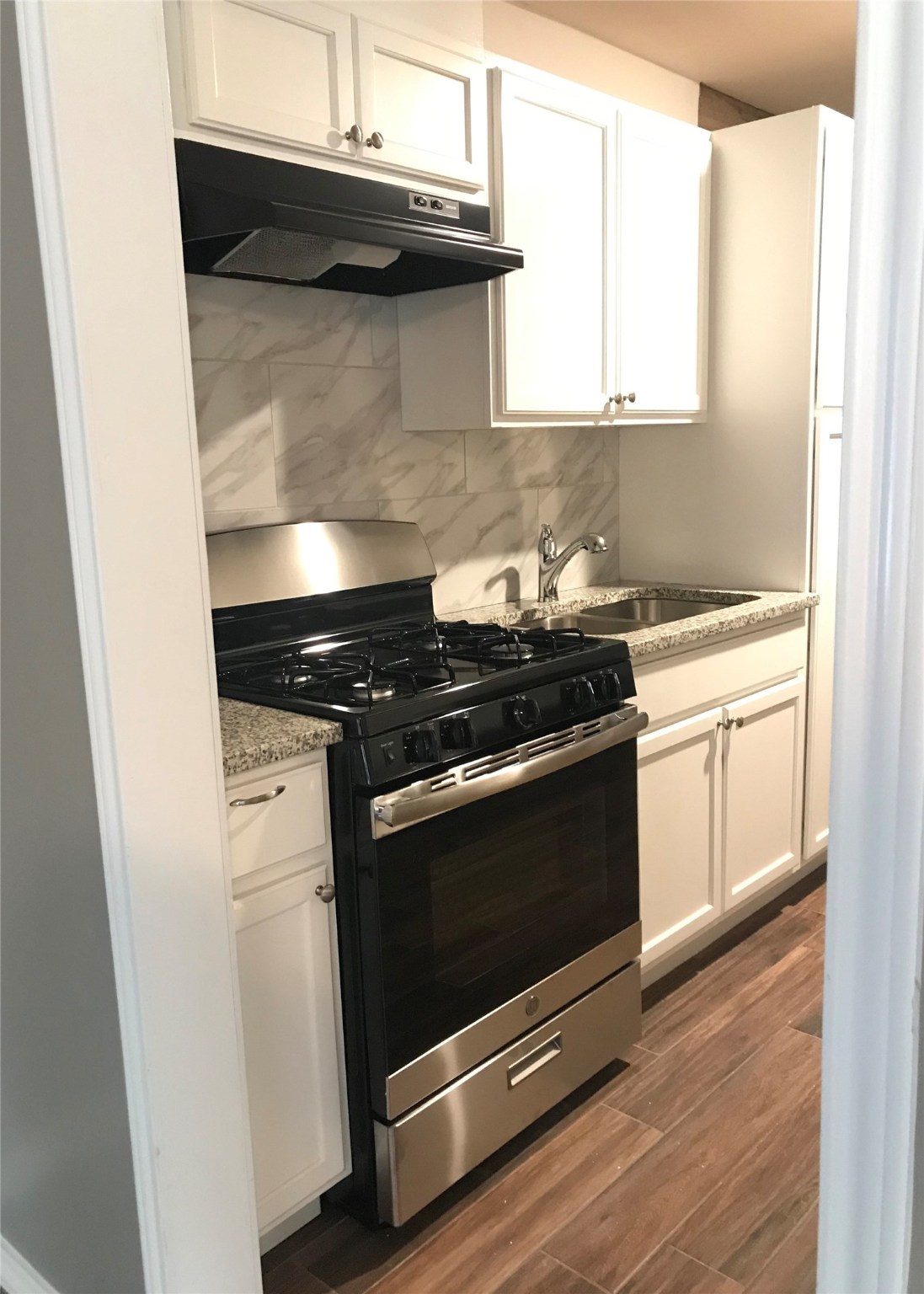 7314 Werner Street Houston, TX 77076 - Photo 3 of 9 a kitchen with stainless steel appliances a stove and white cabinets