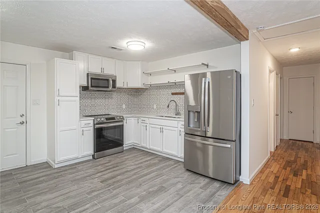 a kitchen with kitchen island wooden floors and stainless steel appliances