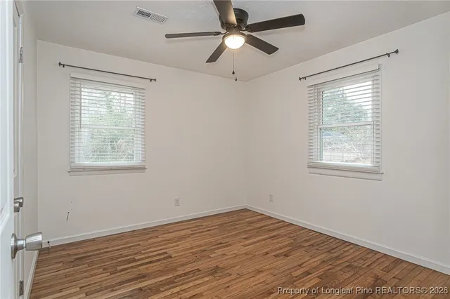 a view of empty room with wooden floor and fan
