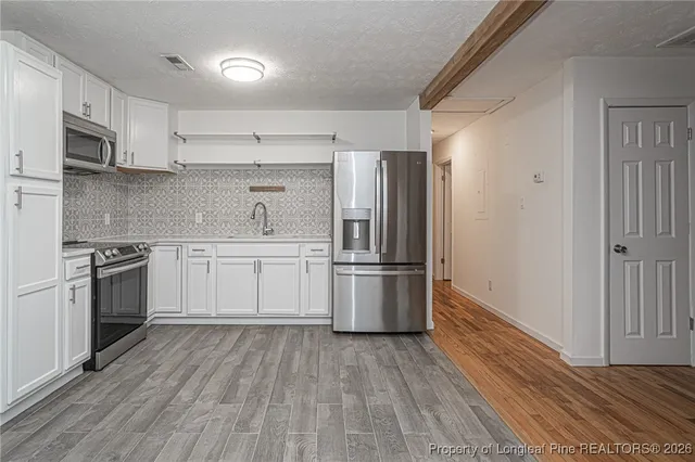 a kitchen with white cabinets stainless steel appliances and sink
