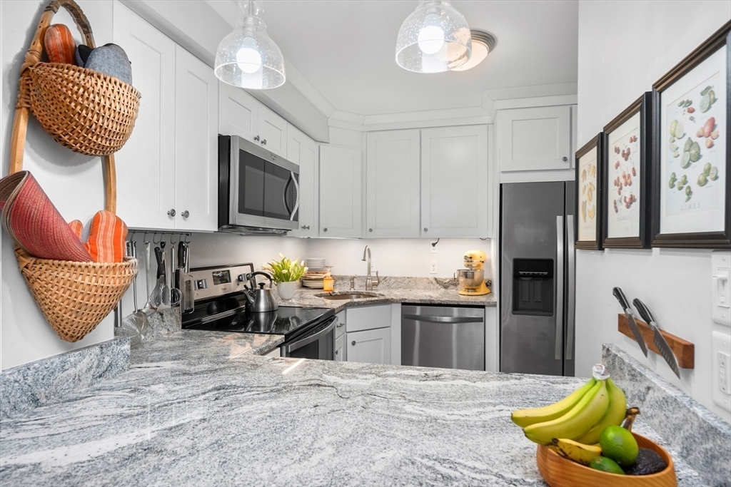 9 Park Hull Ma, Unit 505 Hull, MA 02045 - Photo 13 of 25 a kitchen with stainless steel appliances granite countertop a refrigerator a stove a sink dishwasher and white cabinets with wooden floor