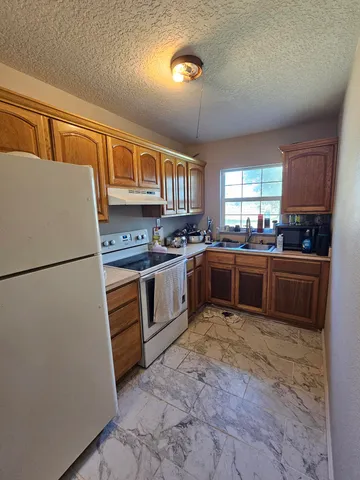 a kitchen with granite countertop a sink stainless steel appliances and a window