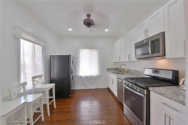 a kitchen with granite countertop kitchen island stainless steel appliances a stove a sink a refrigerator cabinets and a window