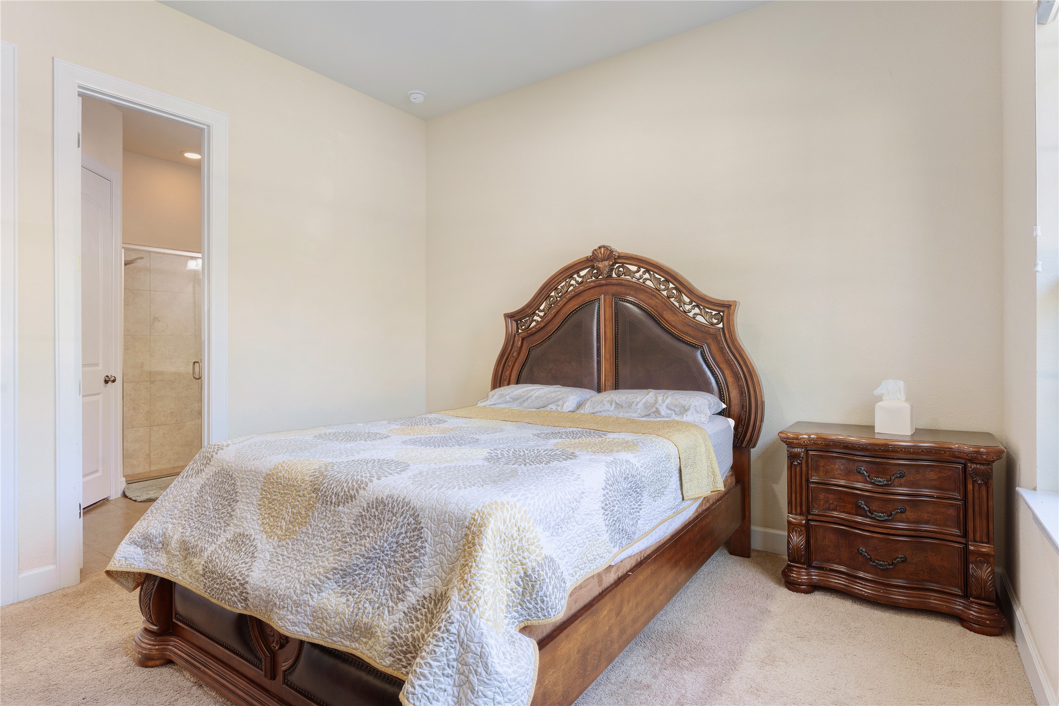 228 Lockhart Loop Georgetown, TX 78628 - Photo 18 of 37 A comfortable bedroom features a richly carved wooden bed frame and easy access to an adjacent bathroom.