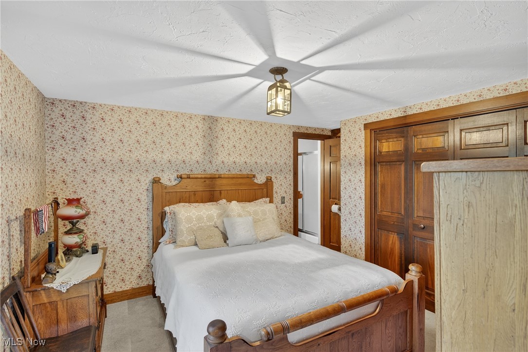 25700 Winona Road Homeworth, OH 44634 - Photo 15 of 49 Bedroom with wallpapered walls, a closet, and a textured ceiling