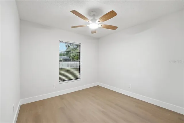 an empty room with a window and a ceiling fan