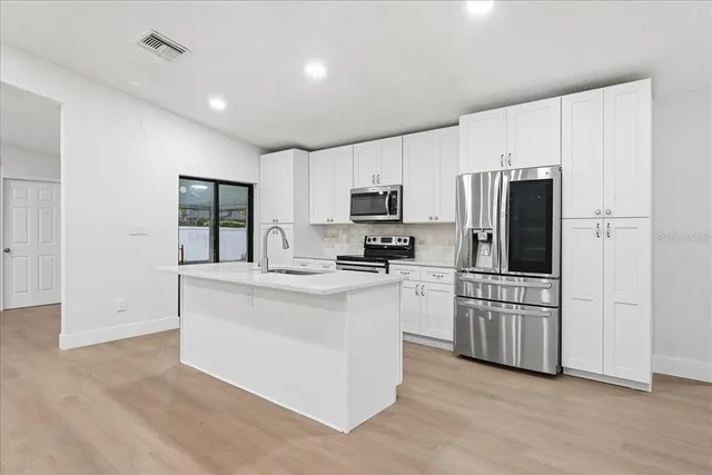 a kitchen with white cabinets and stainless steel appliances