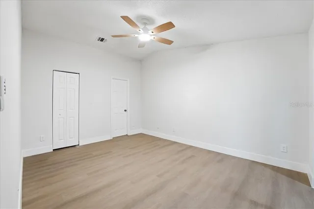 an empty room with a ceiling fan and wooden floor
