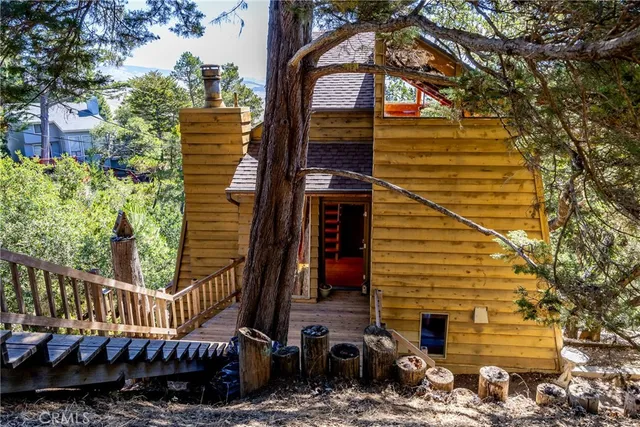 a view of a brick house with a large tree and wooden fence