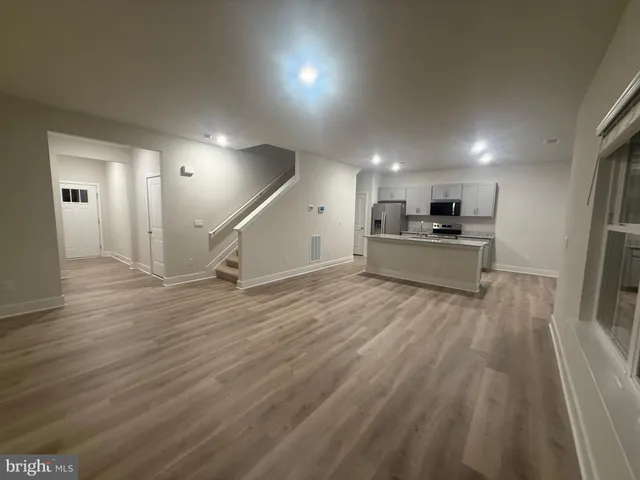 a large kitchen with stainless steel appliances kitchen island a large counter top and a wooden floors