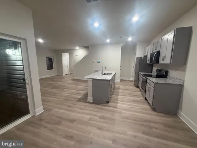 a view of kitchen with microwave stove refrigerator and sink