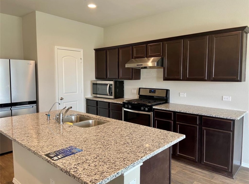 a kitchen with stainless steel appliances granite countertop a sink stove and refrigerator