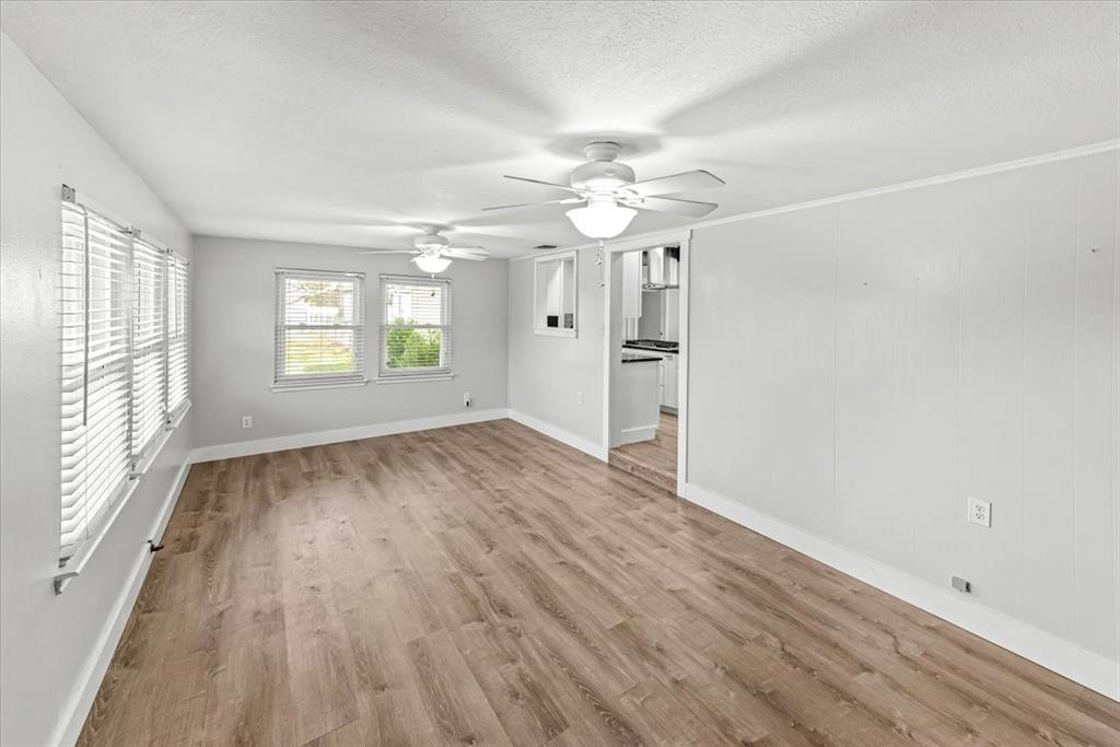 334 County Road 1296 Morgan, TX 76671 - Photo 10 of 32 an empty room with wooden floor chandelier fan and windows