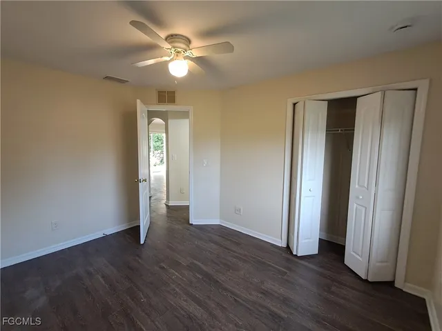 an empty room with wooden floor and a ceiling fan