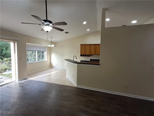 a view of an empty room with a window and wooden floor