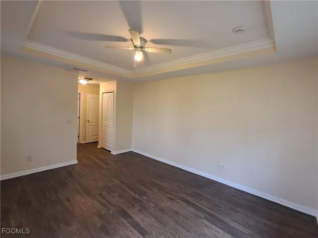an empty room with wooden floor fan and window