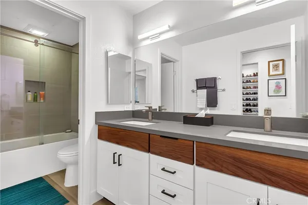 a bathroom with a double vanity sink and mirror with bathtub
