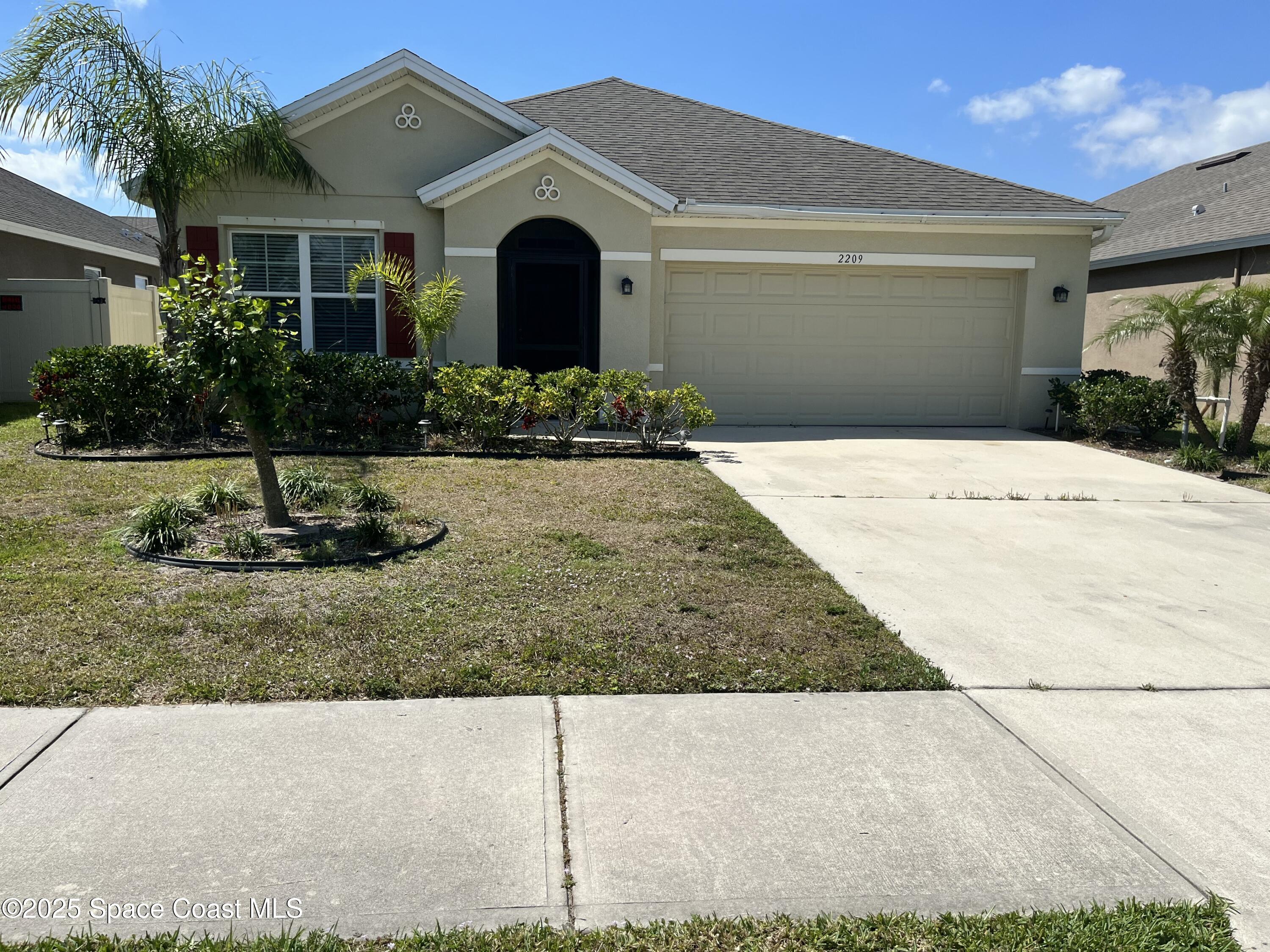 2209 McCormack Way Melbourne, FL 32935 - Photo 3 of 22 a front view of a house with a yard and garage