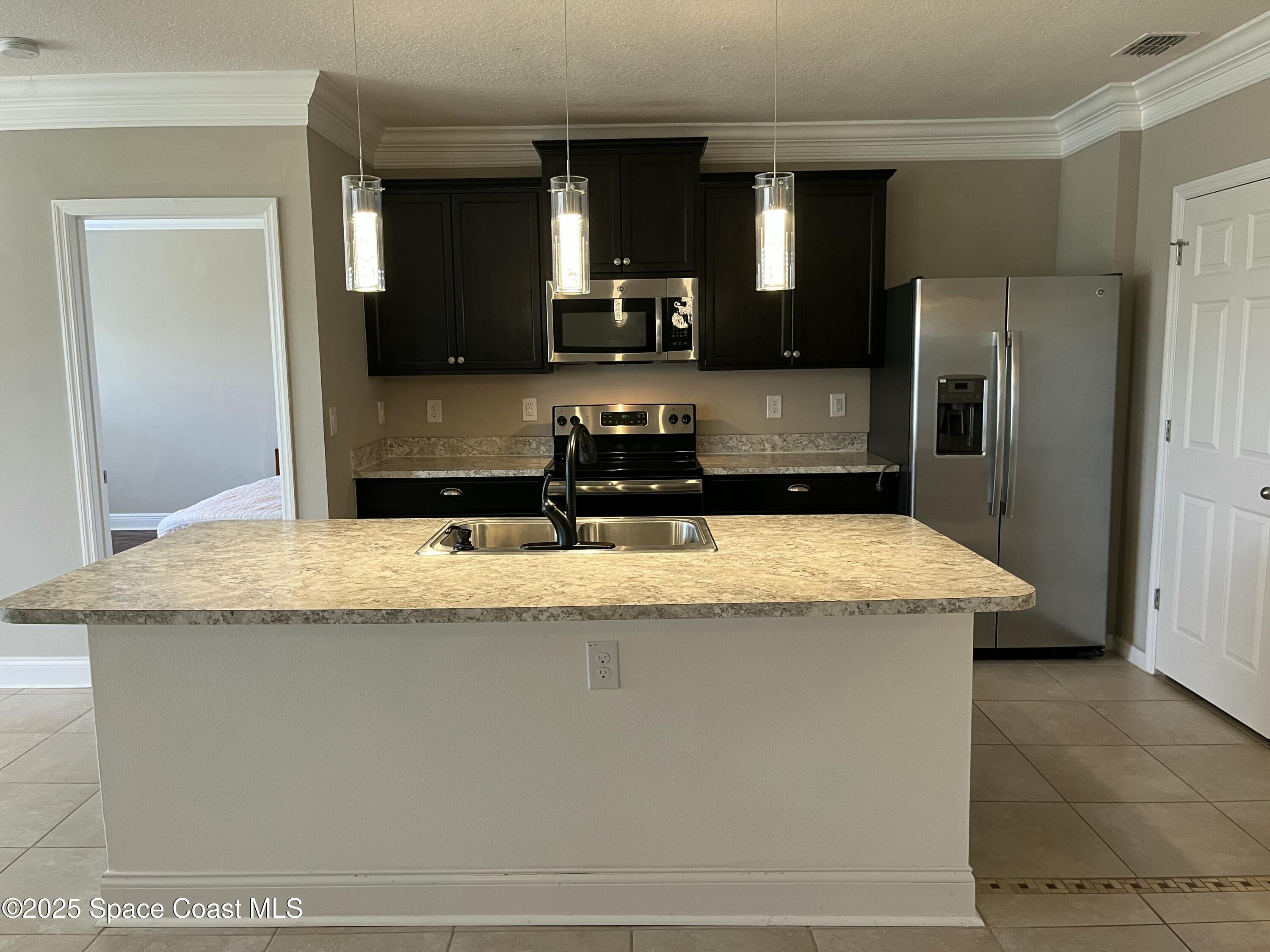 2209 McCormack Way Melbourne, FL 32935 - Photo 4 of 22 a kitchen with kitchen island stainless steel appliances a sink and a refrigerator