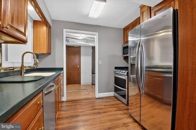 a kitchen with kitchen island granite countertop a sink cabinets and stainless steel appliances