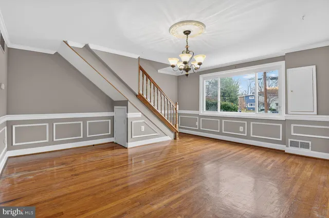 a view of an empty room with wooden floor and stairs