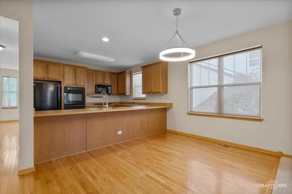 a kitchen with stainless steel appliances granite countertop a refrigerator a sink dishwasher a stove and a dining table with wooden floor