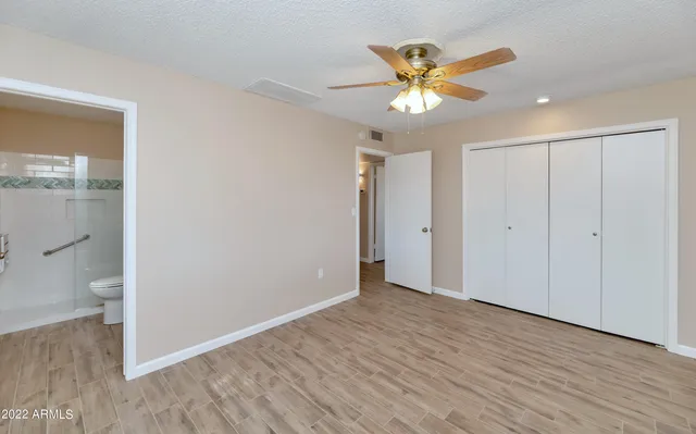 a view of an empty room with wooden floor and a ceiling fan