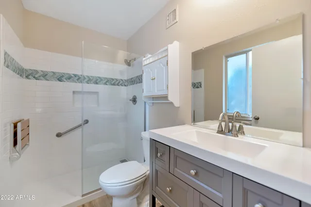 a bathroom with a granite countertop sink a toilet and a mirror