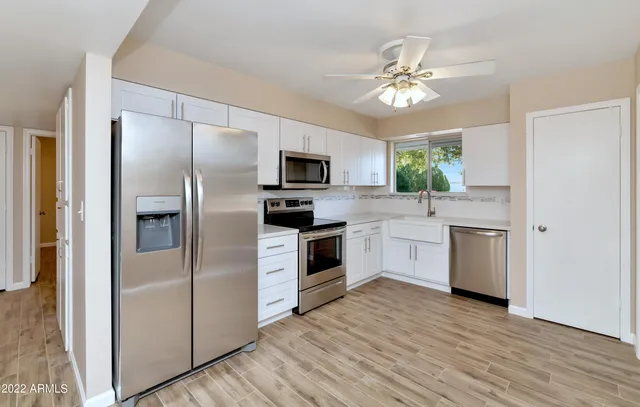 a kitchen with a refrigerator cabinets and wooden floor
