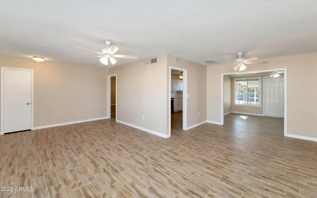 a view of an empty room with window and wooden floor