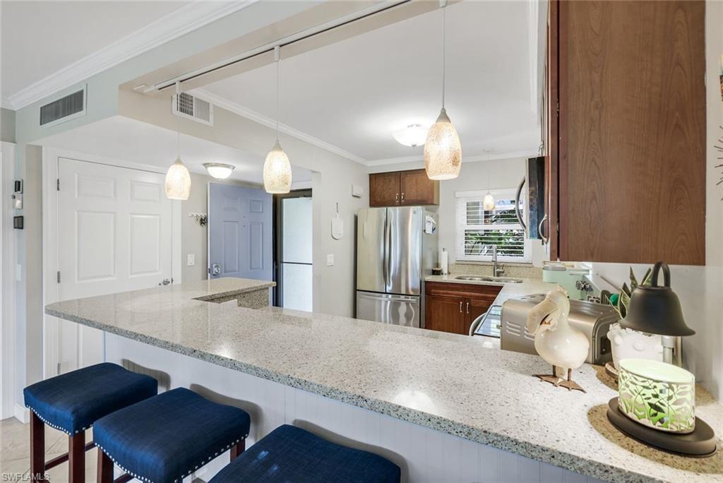 201 Quail Forest Boulevard, Unit 101 Naples, FL 34105 - Photo 15 of 32 a kitchen with stainless steel appliances kitchen island granite countertop a sink and a refrigerator
