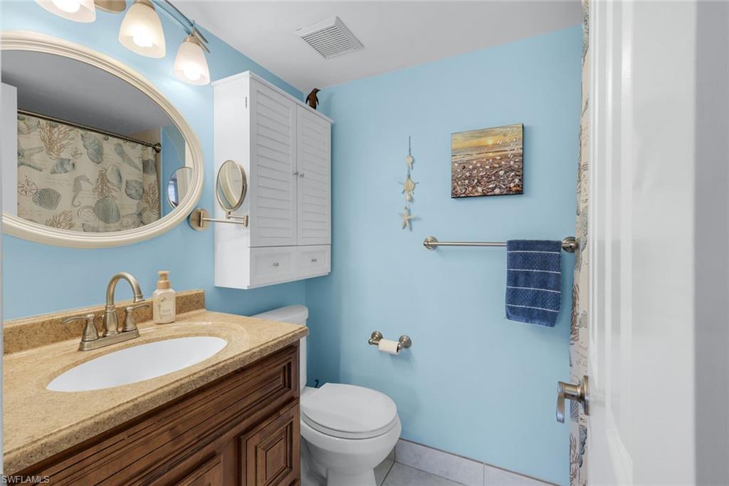 201 Quail Forest Boulevard, Unit 101 Naples, FL 34105 - Photo 19 of 32 a bathroom with a granite countertop toilet a sink and a mirror