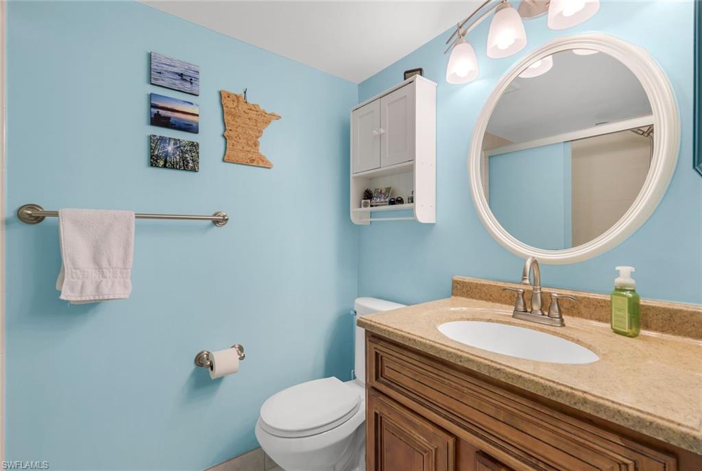 201 Quail Forest Boulevard, Unit 101 Naples, FL 34105 - Photo 21 of 32 a bathroom with a granite countertop toilet sink and mirror