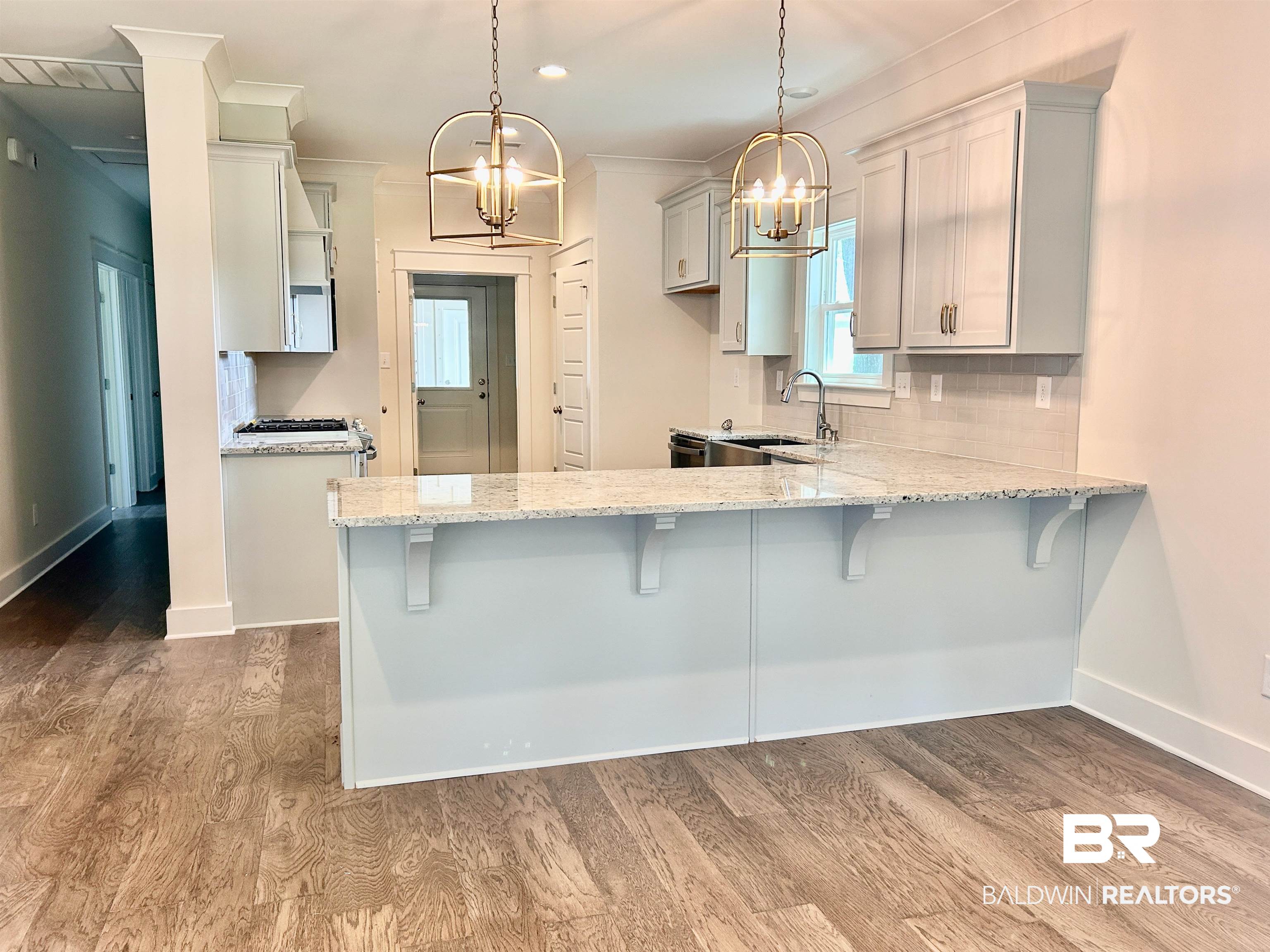 14693 Cedar Street Magnolia Springs, AL 36555 - Photo 6 of 8 Kitchen featuring light wood-type flooring, a chandelier, sink, pendant lighting, and a kitchen bar