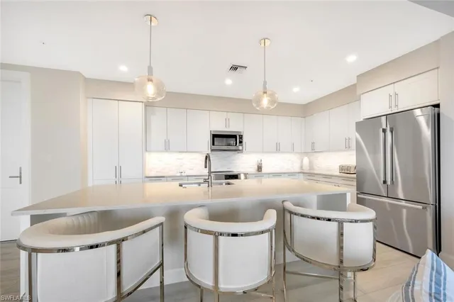 a kitchen with a dining table chairs refrigerator and microwave