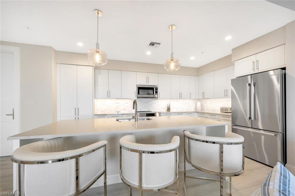 1111 Central Avenue, Unit 511 Naples, FL 34102 - Photo 13 of 50 a kitchen with a dining table chairs refrigerator and microwave