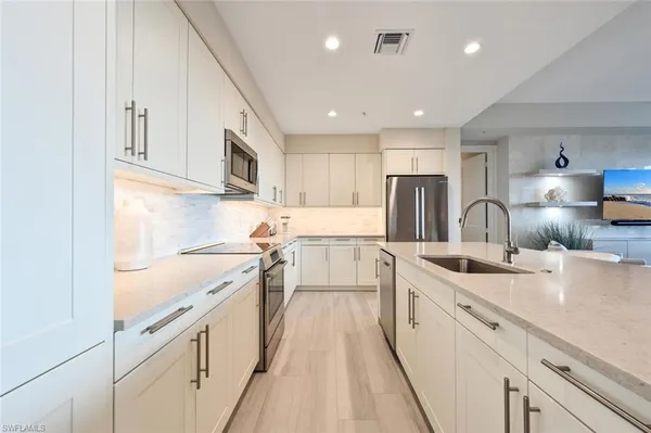 a kitchen with white cabinets sink and stainless steel appliances