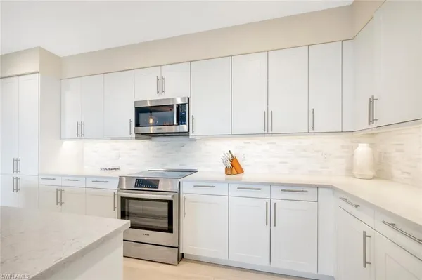 a kitchen with white cabinets and stainless steel appliances