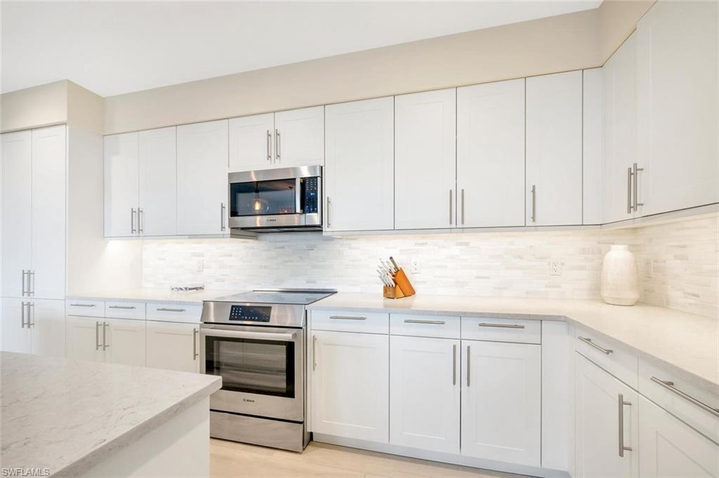 1111 Central Avenue, Unit 511 Naples, FL 34102 - Photo 15 of 50 a kitchen with white cabinets and stainless steel appliances