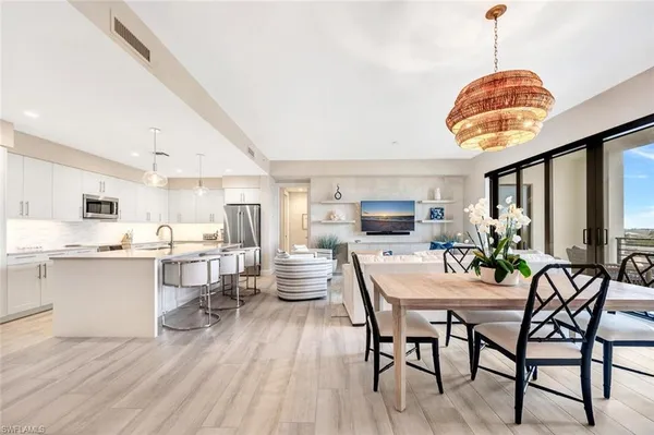 a dining room with stainless steel appliances granite countertop a dining table chairs stove and white cabinets
